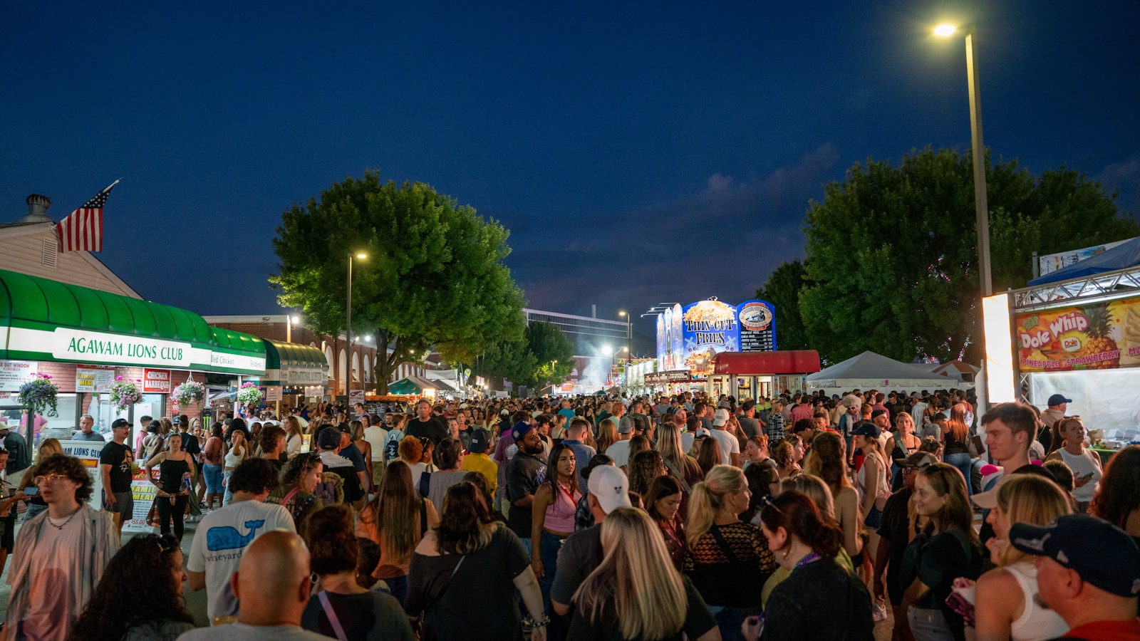 A crowd of people standing around a street at night
